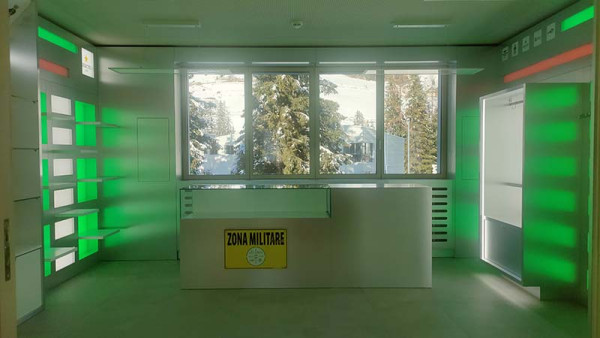 Interno elegante dello shop Zona Militare Key Comunicazione con luci LED verdi e vista invernale a Corvara