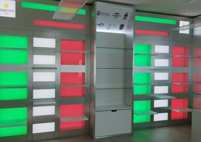Scaffalature moderne con illuminazione LED in rosso e verde nello shop Zona Militare, progetto di Key Comunicazione.