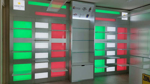 Scaffalature moderne con illuminazione LED in rosso e verde nello shop Zona Militare, progetto di Key Comunicazione.