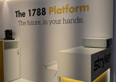 L'immagine mostra uno spazio accogliente con colori luminosi e un'organizzazione funzionale. Il logo Stryker e il claim "The 1788 Platform" sono ben visibili, mentre un'elegante reception invita i visitatori a interagire. L'attenzione ai dettagli e la cura nell'illuminazione creano un'atmosfera professionale e invitante. Lo stand, progettato da Key Comunicazione, riflette l'eccellenza e l'innovazione di Stryker, offrendo un'esperienza coinvolgente per i partecipanti al congresso.